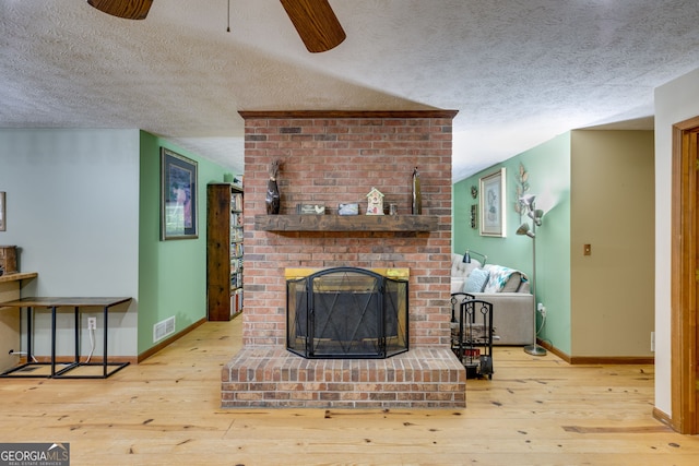 220 Gamble Dr, Carrollton, GA 30116 - living room featuring a textured ceiling, hardwood / wood-style floors, ceiling fan, and a fireplace