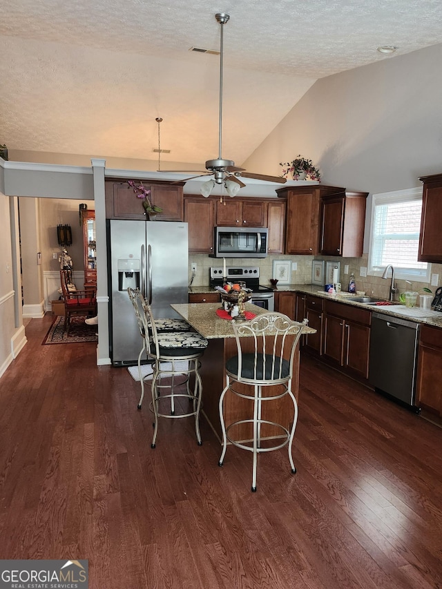 979 Simonton Dr, Lawrenceville, GA 30045 - kitchen with stainless steel appliances, tasteful backsplash, dark wood-style flooring, a breakfast bar, and a kitchen island