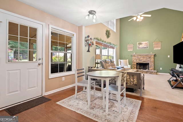 5340 Harris Creek Dr, Cumming, GA 30040 - dining area featuring a stone fireplace, wood finished floors, a ceiling fan, and a high ceiling