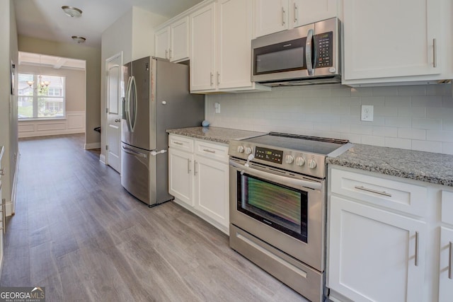 116 Sophie Cir, Locust Grove, GA 30248 - kitchen with appliances with stainless steel finishes, light wood-type flooring, white cabinetry, tasteful backsplash, and light stone counters