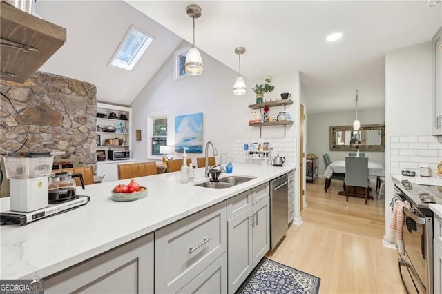 2653 Partridge Trl, Duluth, GA 30097 - kitchen with appliances with stainless steel finishes, a skylight, light wood-style flooring, pendant lighting, and backsplash