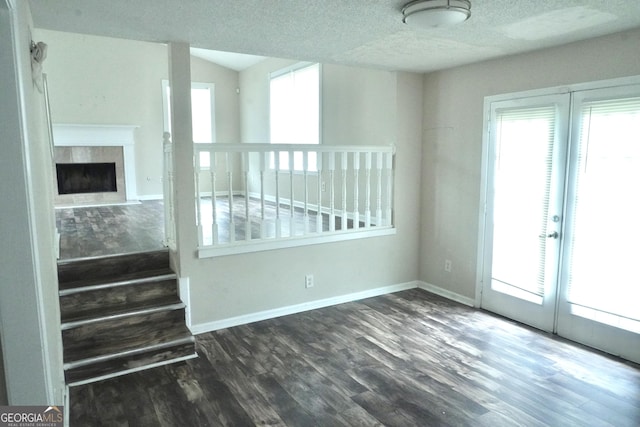 5761 Antelope Trl, Atlanta, GA 30349 - unfurnished living room with plenty of natural light, wood finished floors, a fireplace, a textured ceiling, and french doors
