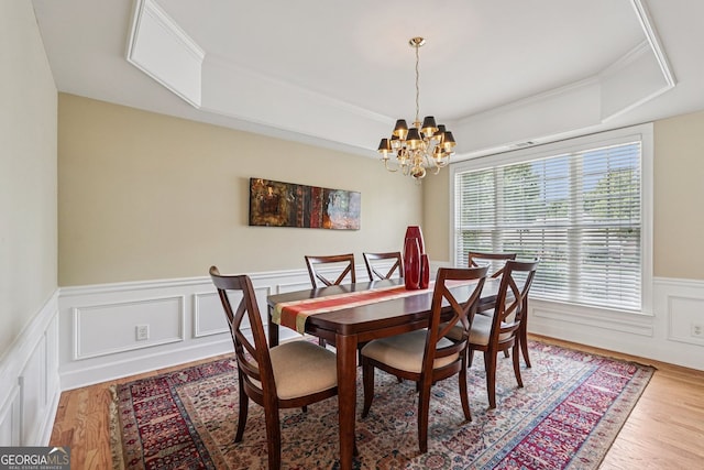 25 Hampreston Ct, Alpharetta, GA 30022 - dining room featuring a raised ceiling, a chandelier, light wood-type flooring, a wainscoted wall, and a decorative wall