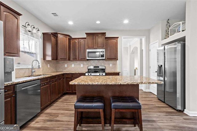 1786 Jameson Cir, Lawrenceville, GA 30043 - kitchen featuring stainless steel appliances, a kitchen island, wood finished floors, tasteful backsplash, and a kitchen breakfast bar