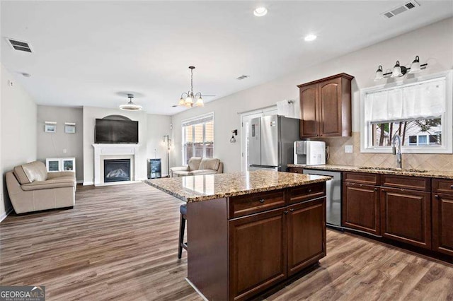 1786 Jameson Cir, Lawrenceville, GA 30043 - kitchen with appliances with stainless steel finishes, wood finished floors, a fireplace, a center island, and backsplash