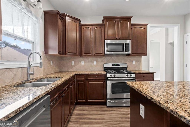 1786 Jameson Cir, Lawrenceville, GA 30043 - kitchen with appliances with stainless steel finishes, light stone counters, wood finished floors, dark brown cabinets, and backsplash