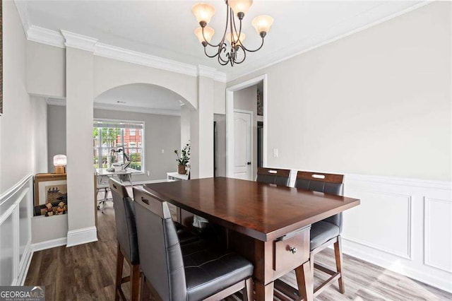 1786 Jameson Cir, Lawrenceville, GA 30043 - dining room featuring arched walkways, a chandelier, wood finished floors, ornamental molding, and wainscoting