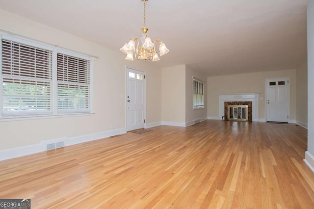508 College St, Bowdon, GA 30108 - unfurnished living room with a chandelier, light wood-style floors, and a fireplace