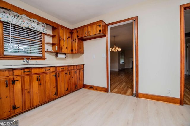 508 College St, Bowdon, GA 30108 - kitchen with light wood-style floors, a chandelier, brown cabinetry, light countertops, and open shelves