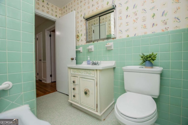 508 College St, Bowdon, GA 30108 - bathroom featuring wallpapered walls, vanity, tile walls, and a wainscoted wall
