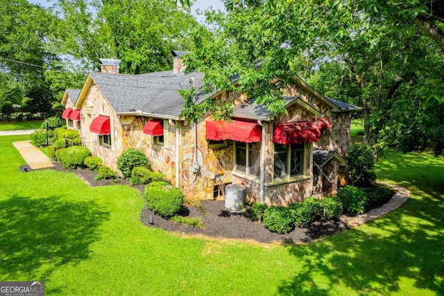 508 College St, Bowdon, GA 30108 - back of house featuring stone siding, a lawn, a shingled roof, and a chimney