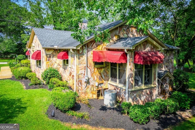 508 College St, Bowdon, GA 30108 - view of front facade with stone siding, a shingled roof, a chimney, and a front lawn