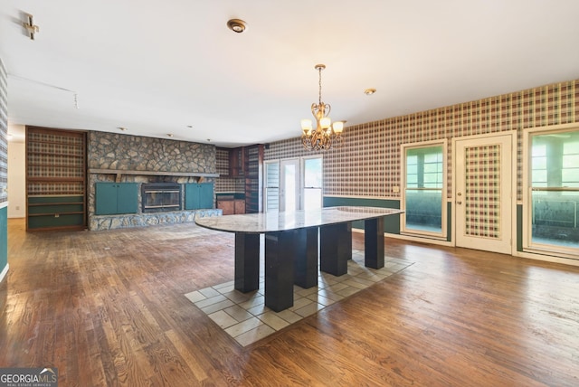 290 Bear Cave Trl, Lakemont, GA 30552 - kitchen with wood finished floors, a chandelier, a stone fireplace, wallpapered walls, and hanging light fixtures
