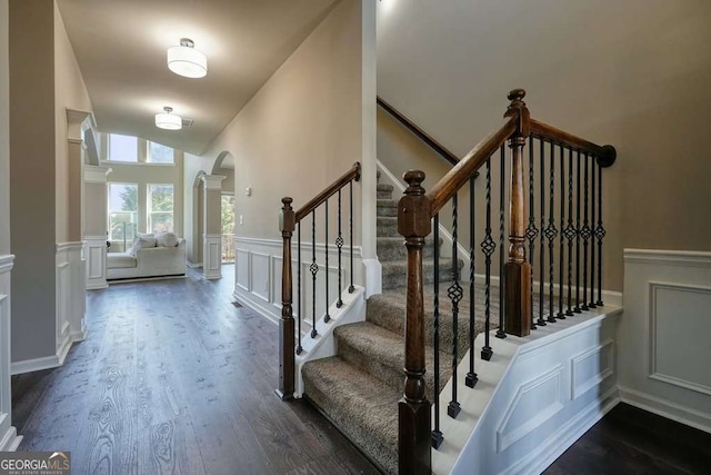 6665 Flagstone Ct, Cumming, GA 30028 - stairs featuring arched walkways, wood finished floors, wainscoting, a decorative wall, and vaulted ceiling