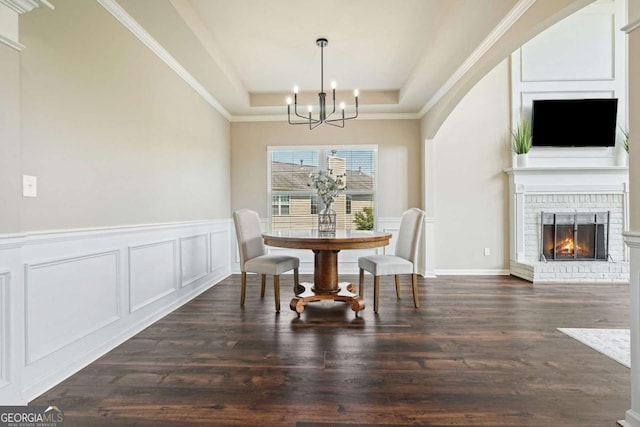 6665 Flagstone Ct, Cumming, GA 30028 - dining area with a chandelier, a tray ceiling, dark wood-type flooring, a decorative wall, and a fireplace