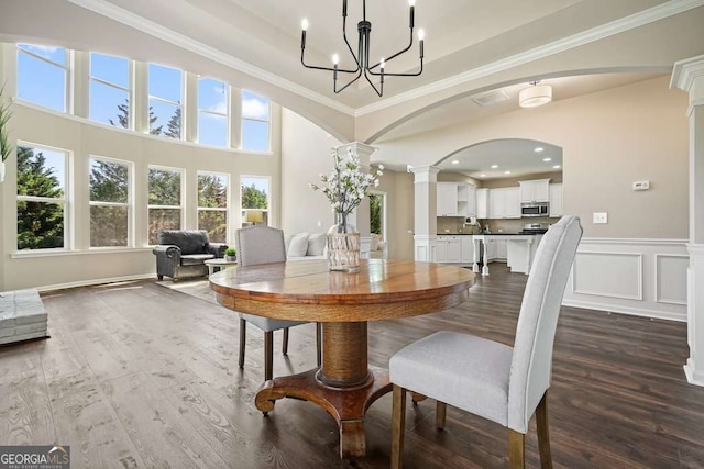 6665 Flagstone Ct, Cumming, GA 30028 - dining space with dark wood-type flooring, ornate columns, a chandelier, ornamental molding, and arched walkways