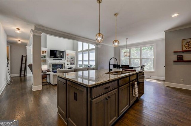 6863 Lake Sterling, Flowery Branch, GA 30542 - kitchen with a glass covered fireplace, crown molding, light stone countertops, dark wood-style floors, and decorative light fixtures