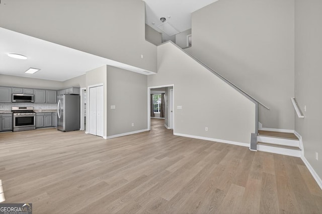 591 Wendlebury Ct, Alpharetta, GA 30004 - unfurnished living room featuring light wood finished floors, a towering ceiling, and stairs