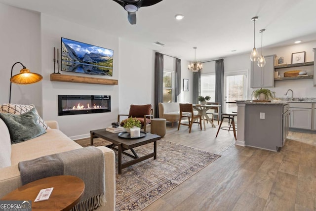 235 Ivey Ter, Temple, GA 30179 - living area with light wood-type flooring, a glass covered fireplace, a chandelier, recessed lighting, and ceiling fan