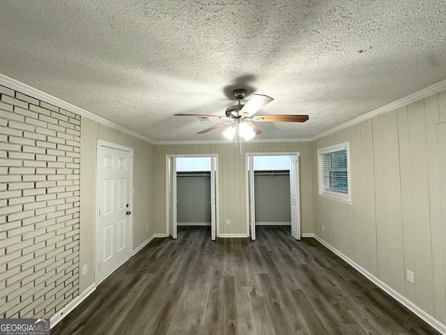 2644 Connally Dr, East Point, GA 30344 - unfurnished bedroom with dark wood-style flooring, two closets, brick wall, crown molding, and a textured ceiling
