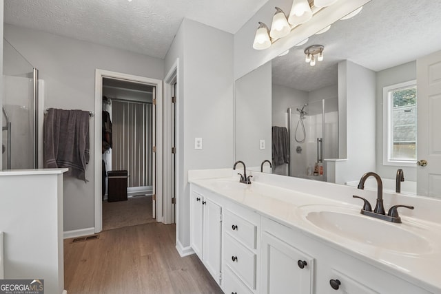 1535 Smoke Hill Dr, Hoschton, GA 30548 - bathroom featuring wood finished floors, a shower stall, double vanity, and a textured ceiling