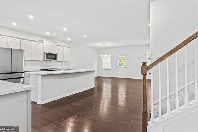 400 Paulownia Cir, Mcdonough, GA 30253 - kitchen featuring appliances with stainless steel finishes, dark wood-style flooring, light countertops, recessed lighting, and a center island with sink