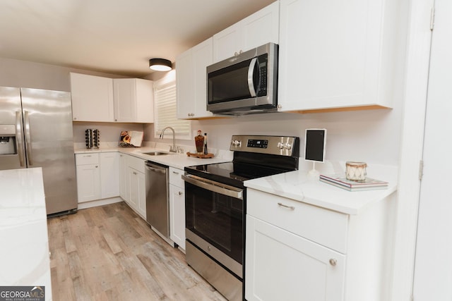 6914 N Baggett Rd, Douglasville, GA 30134 - kitchen featuring appliances with stainless steel finishes, light wood finished floors, white cabinets, and light stone counters