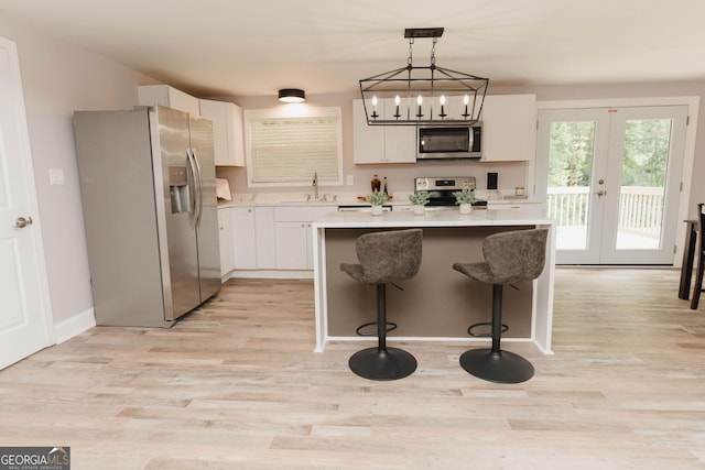 6914 N Baggett Rd, Douglasville, GA 30134 - kitchen featuring stainless steel appliances, a center island, light wood-style flooring, white cabinetry, and light countertops