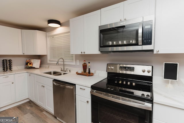 6914 N Baggett Rd, Douglasville, GA 30134 - kitchen with appliances with stainless steel finishes, light wood-style floors, white cabinets, and light stone counters
