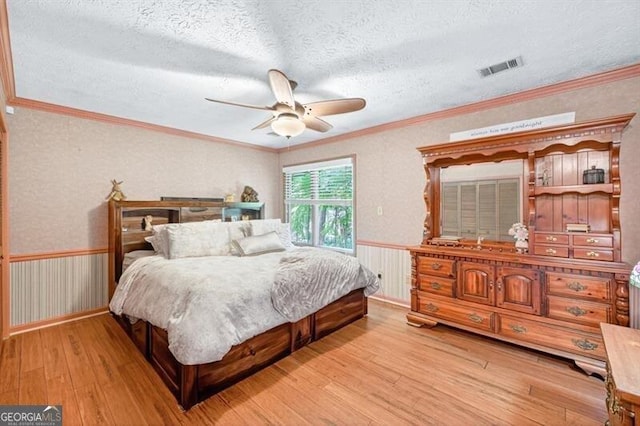 686 Hillwood Ct, Dacula, GA 30019 - bedroom featuring light wood-style flooring, a wainscoted wall, a textured ceiling, crown molding, and ceiling fan