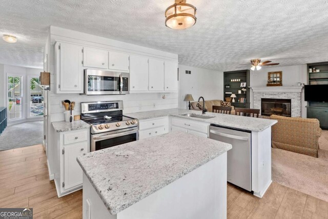 5055 Southland Dr, Woodstock, GA 30188 - kitchen featuring stainless steel appliances, a peninsula, light wood-style flooring, ceiling fan, and white cabinets