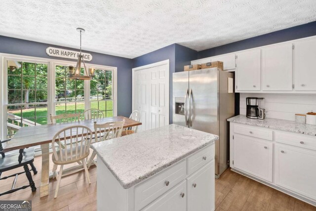 5055 Southland Dr, Woodstock, GA 30188 - kitchen with stainless steel fridge with ice dispenser, white cabinetry, light wood-style floors, a center island, and decorative light fixtures