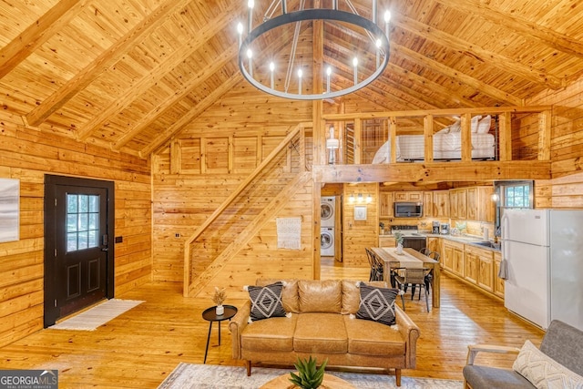 371 Abbott Top Rd, Ellijay, GA 30540 - living area featuring stacked washing machine and dryer, wood walls, high vaulted ceiling, a wood ceiling with exposed beams, and light wood-style floors