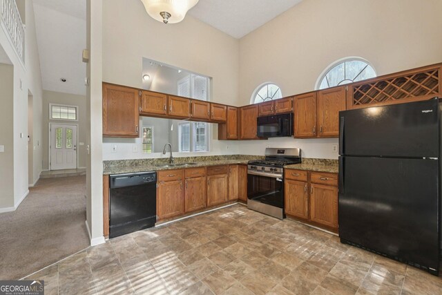 686 Shore Ln, Lithonia, GA 30058 - kitchen featuring black appliances, a towering ceiling, brown cabinets, and healthy amount of natural light