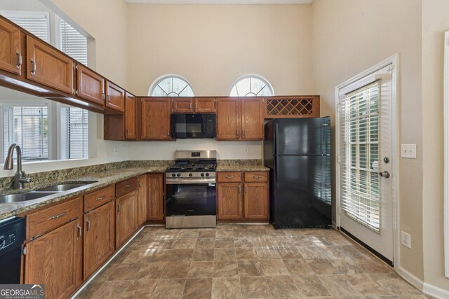 686 Shore Ln, Lithonia, GA 30058 - kitchen featuring black appliances, a towering ceiling, plenty of natural light, and brown cabinetry