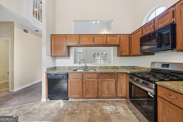 686 Shore Ln, Lithonia, GA 30058 - kitchen with black appliances, a high ceiling, brown cabinets, light stone counters, and plenty of natural light