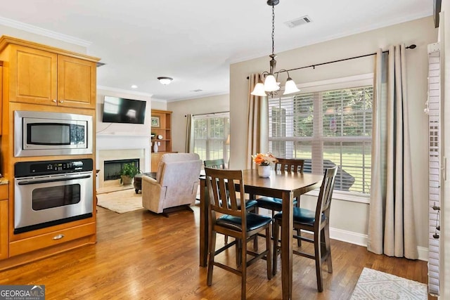 7198 Golfside Dr SE, Covington, GA 30014 - dining area featuring a chandelier, ornamental molding, dark wood finished floors, and a fireplace