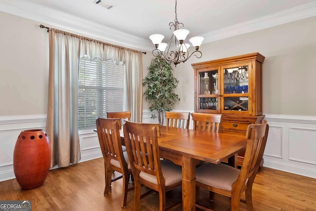 7198 Golfside Dr SE, Covington, GA 30014 - dining area featuring a chandelier, ornamental molding, a decorative wall, wood finished floors, and wainscoting
