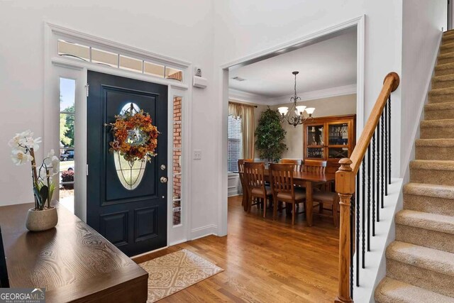 7198 Golfside Dr SE, Covington, GA 30014 - entryway featuring stairway, a chandelier, light wood-style floors, and ornamental molding