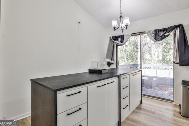 3915 Basil Way SW, Atlanta, GA 30331 - kitchen with dark countertops, a chandelier, white cabinets, light wood-type flooring, and decorative light fixtures