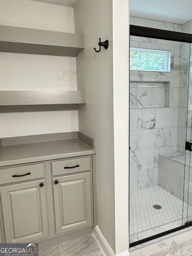 750 Flintlock Dr, Dacula, GA 30019 - bathroom featuring marble finish floors, a marble finish shower, and a textured ceiling