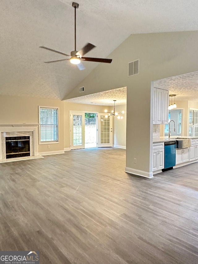 750 Flintlock Dr, Dacula, GA 30019 - unfurnished living room with high vaulted ceiling, a ceiling fan, a chandelier, a textured ceiling, and wood finished floors