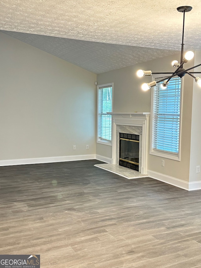 750 Flintlock Dr, Dacula, GA 30019 - unfurnished living room featuring a textured ceiling, a premium fireplace, wood finished floors, a chandelier, and lofted ceiling