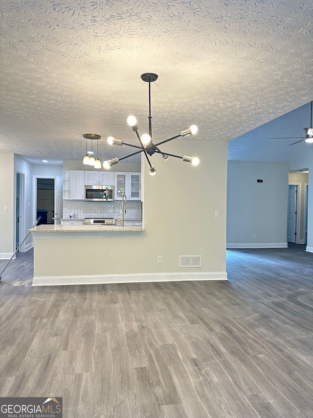 750 Flintlock Dr, Dacula, GA 30019 - unfurnished living room with a textured ceiling, dark wood finished floors, a chandelier, and ceiling fan