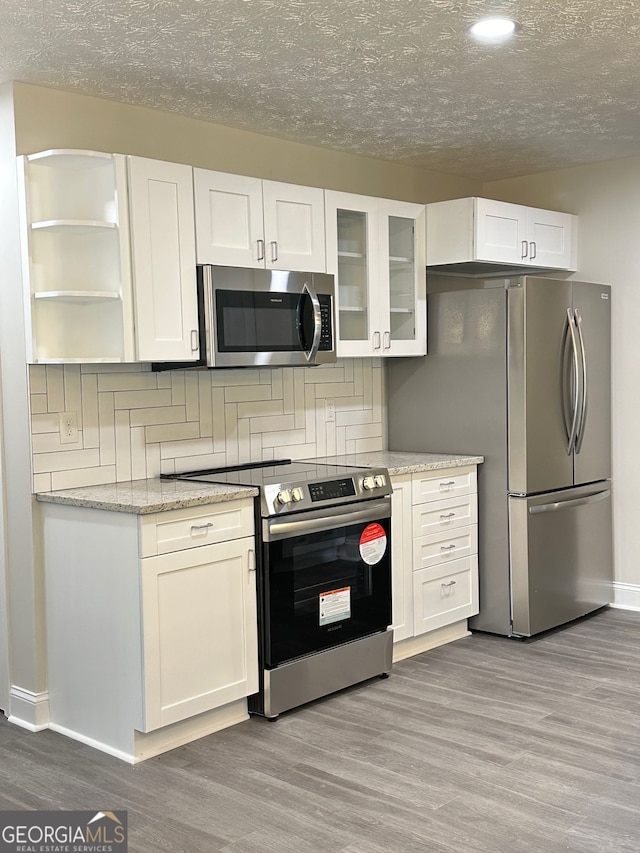 750 Flintlock Dr, Dacula, GA 30019 - kitchen featuring stainless steel appliances, light wood-type flooring, white cabinets, open shelves, and decorative backsplash