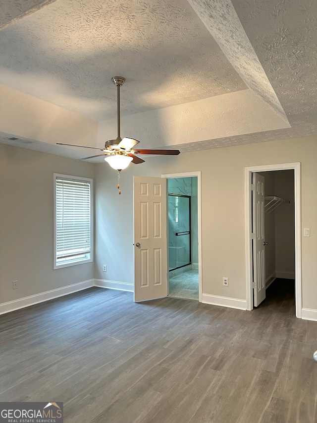 750 Flintlock Dr, Dacula, GA 30019 - unfurnished bedroom featuring a textured ceiling, dark wood-style flooring, a walk in closet, and ceiling fan