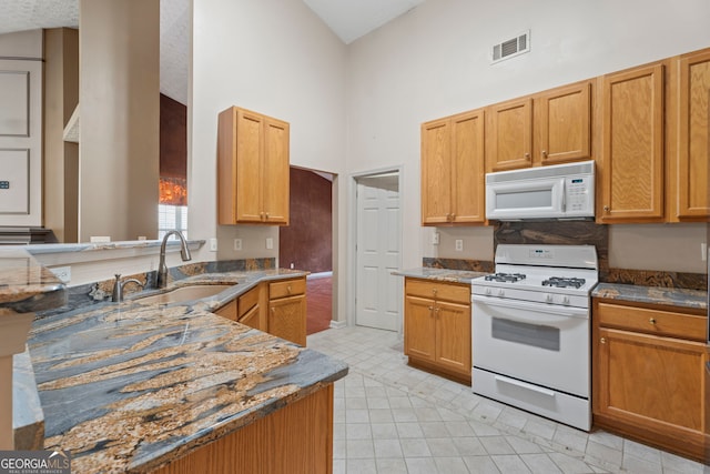 377 Avian Forest Dr, Stockbridge, GA 30281 - kitchen featuring white appliances, high vaulted ceiling, a peninsula, dark stone counters, and light tile patterned floors