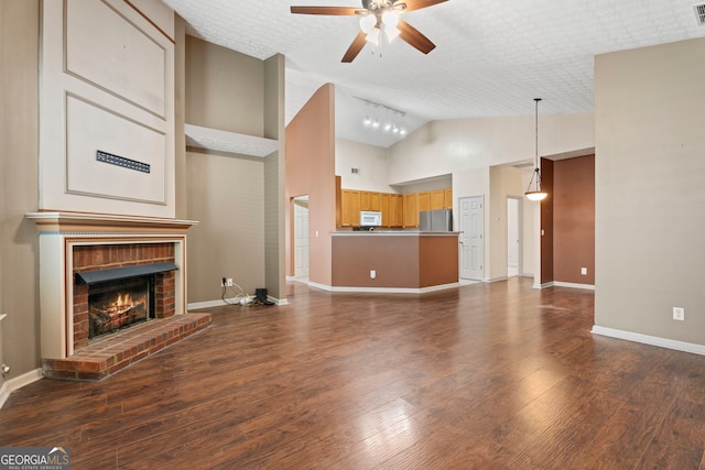 377 Avian Forest Dr, Stockbridge, GA 30281 - unfurnished living room featuring a ceiling fan, a brick fireplace, dark wood-style flooring, and high vaulted ceiling
