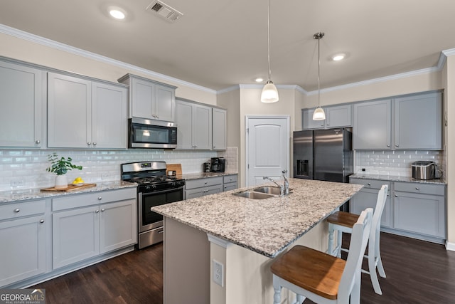 5804 Screech Owl Dr, Flowery Branch, GA 30542 - kitchen featuring appliances with stainless steel finishes, gray cabinets, dark wood-style floors, decorative backsplash, and a kitchen breakfast bar