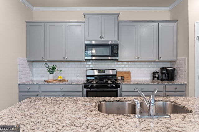 5804 Screech Owl Dr, Flowery Branch, GA 30542 - kitchen with stainless steel microwave, gas range oven, gray cabinetry, crown molding, and backsplash